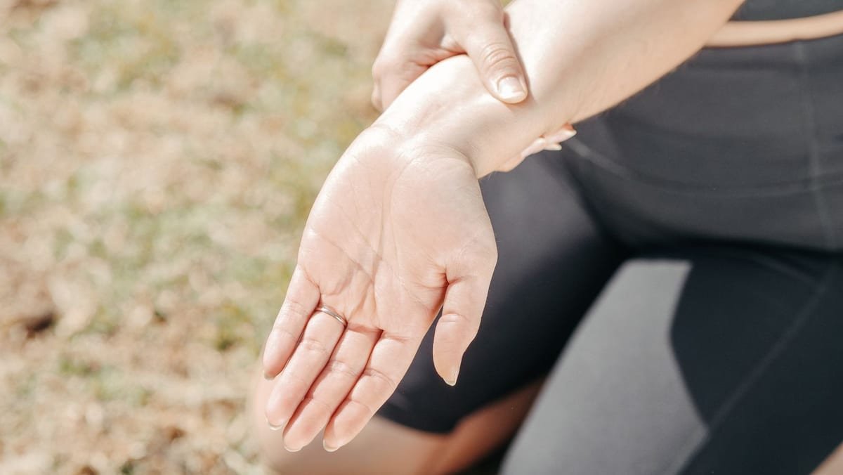 Woman holding her wrist and open palm as if easing hand and finger pain