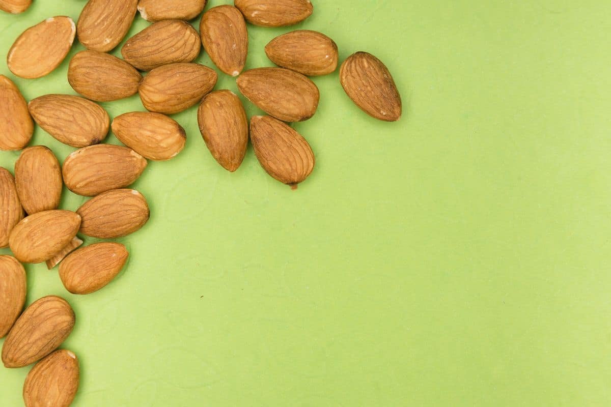 Raw almonds spilled across a soft green surface &mdash; almonds are one of the most magnesium-rich foods