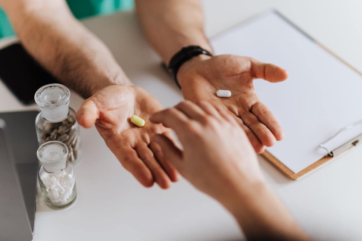 Healthcare professional showing supplement capsules to a patient across a desk during a consultation